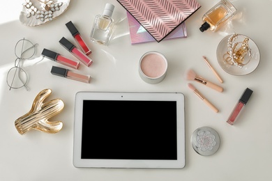 Flat lay composition with tablet and cosmetic accessories on light background, space for design. Blogger's workplace