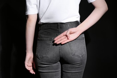 Photo of Woman showing open palm behind her back on black background, back view