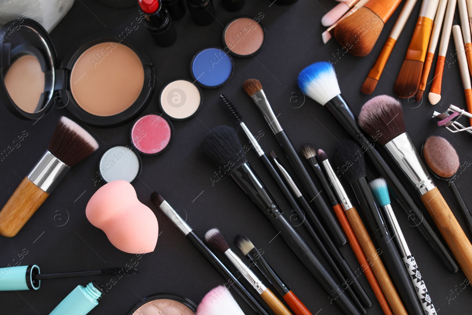 Photo of Flat lay composition with makeup brushes and cosmetic products on black background