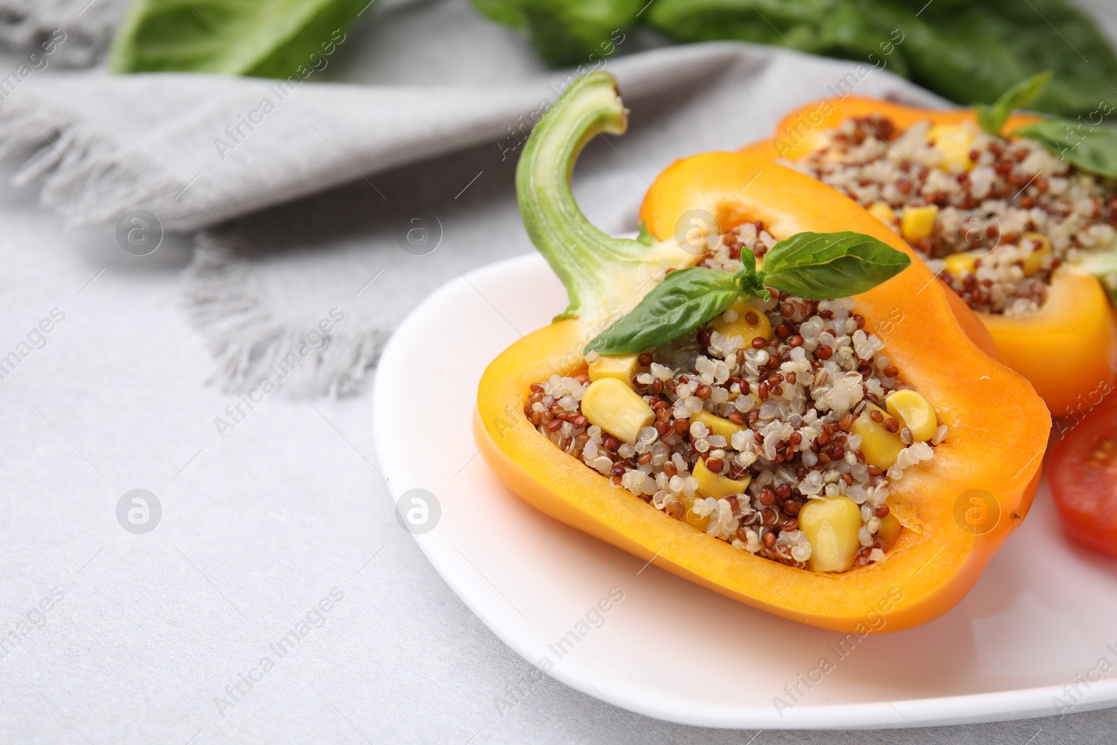 Photo of Quinoa stuffed bell pepper with basil on light table, closeup. Space for text