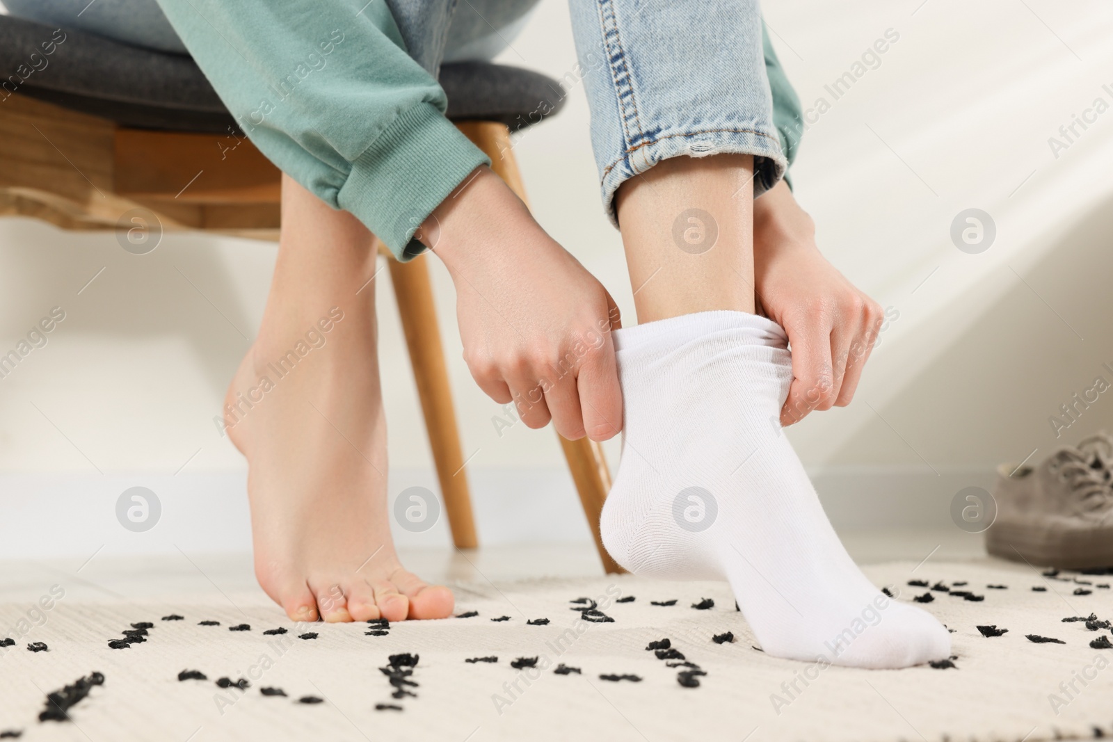 Photo of Woman putting on white socks at home, closeup