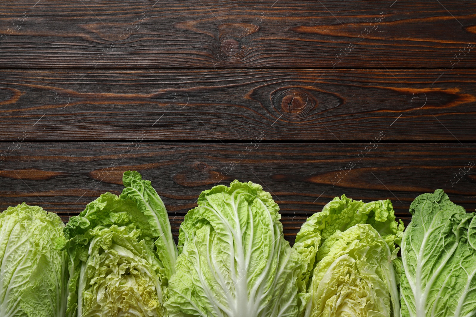Photo of Fresh ripe Chinese cabbages on wooden table, flat lay. Space for text