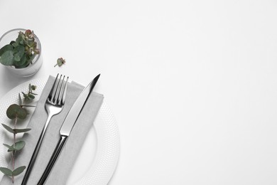 Photo of Stylish setting with cutlery and eucalyptus leaves on white background, top view. Space for text