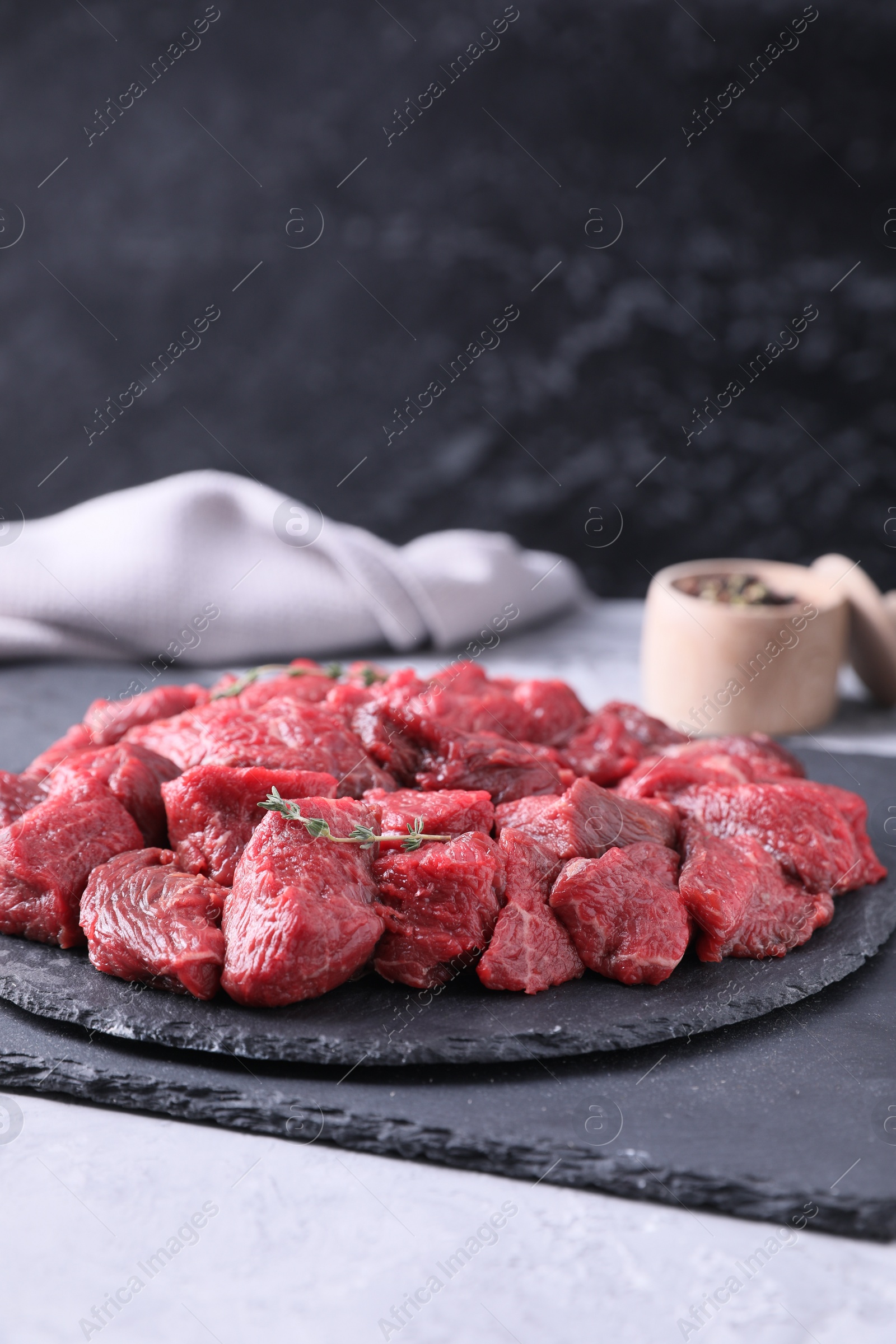 Photo of Pieces of raw beef meat and thyme sprigs on grey textured table. Space for text