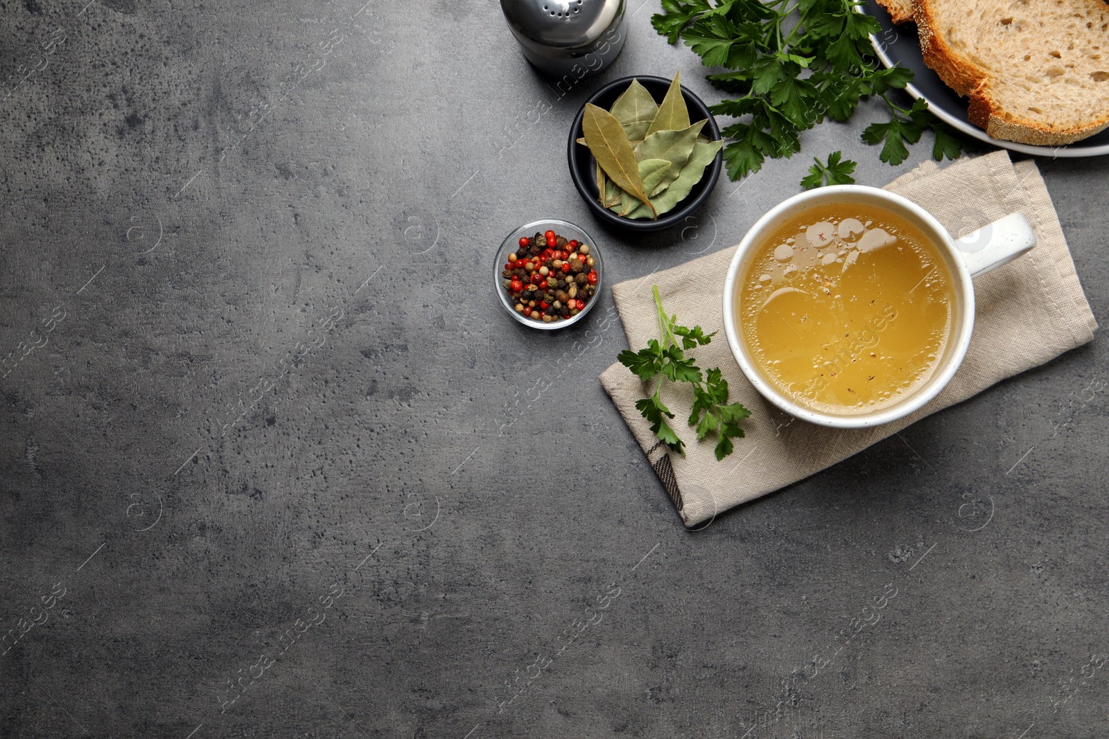 Photo of Hot delicious bouillon in cup on grey table, flat lay. Space for text