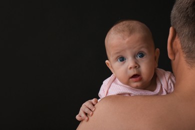 Father with his little baby on black background. Space for text