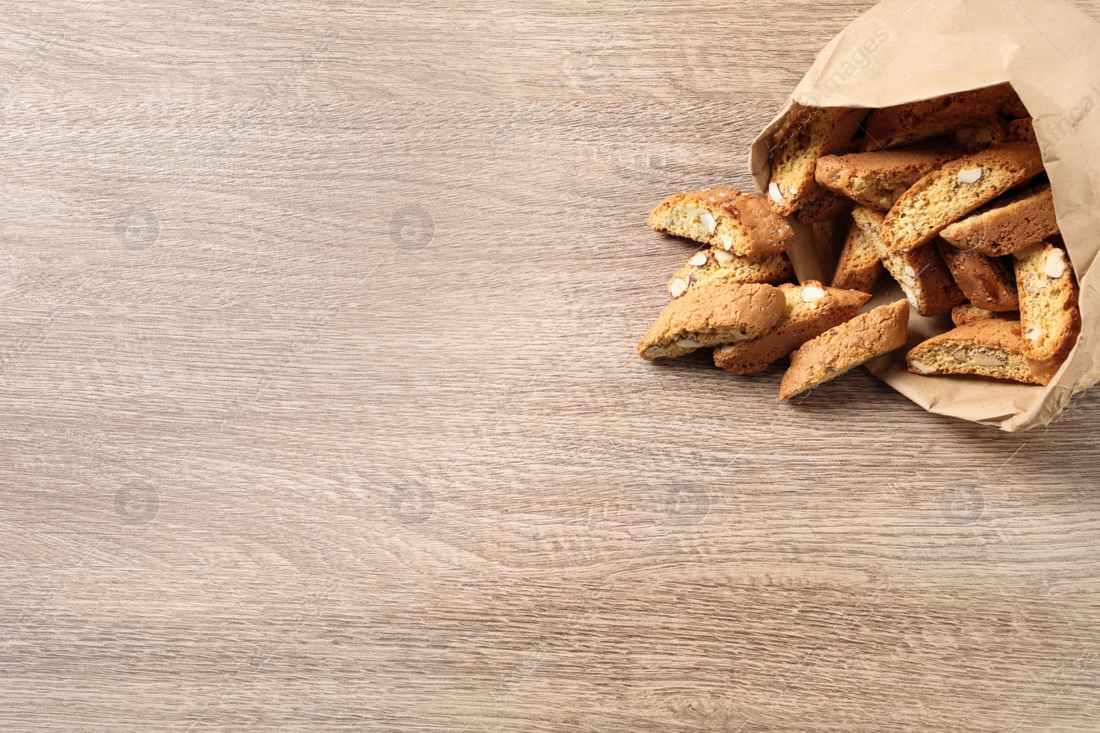 Photo of Traditional Italian almond biscuits (Cantucci) on wooden table, space for text