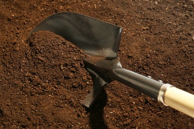 Photo of Metal shovel on fertile soil. Gardening tool