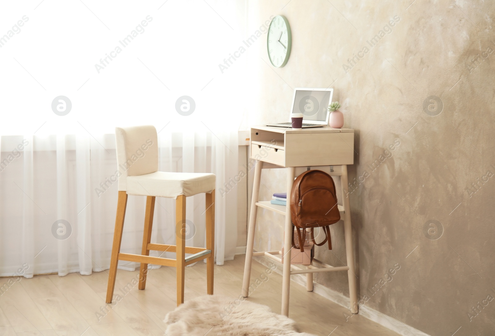 Photo of High wooden table with laptop as stand up workplace in modern interior