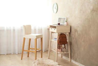 High wooden table with laptop as stand up workplace in modern interior