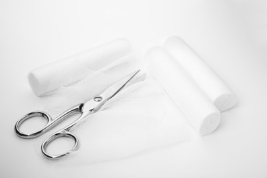 Photo of Medical bandage rolls and scissors on white background