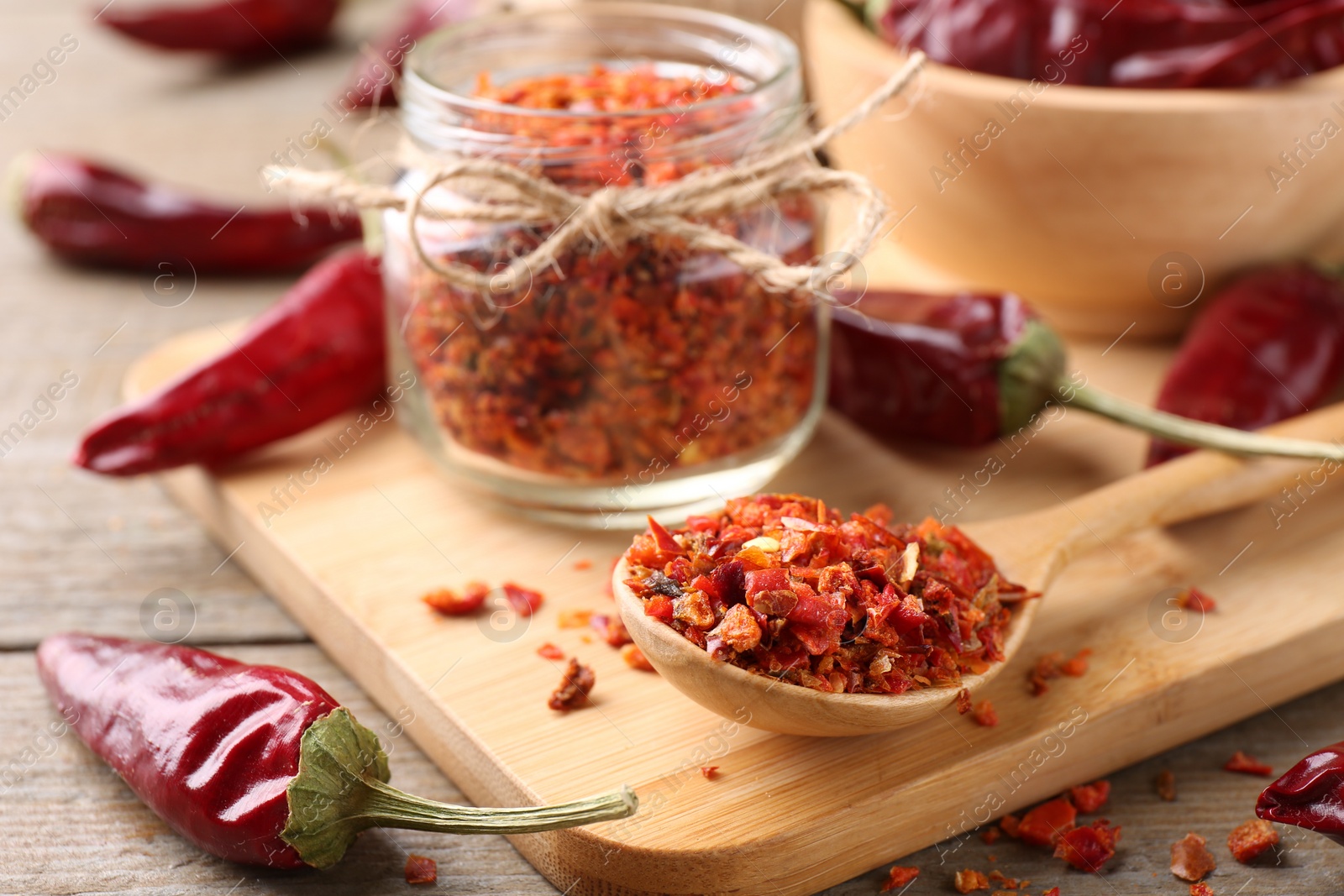 Photo of Chili pepper flakes and pods on wooden table, closeup