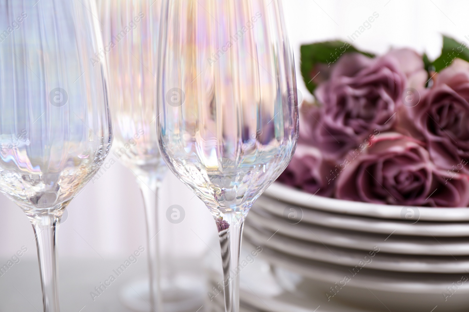 Photo of Set of glasses and dishes with flowers on light background, closeup