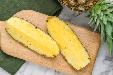 Cut tasty ripe pineapple on white marble table, top view