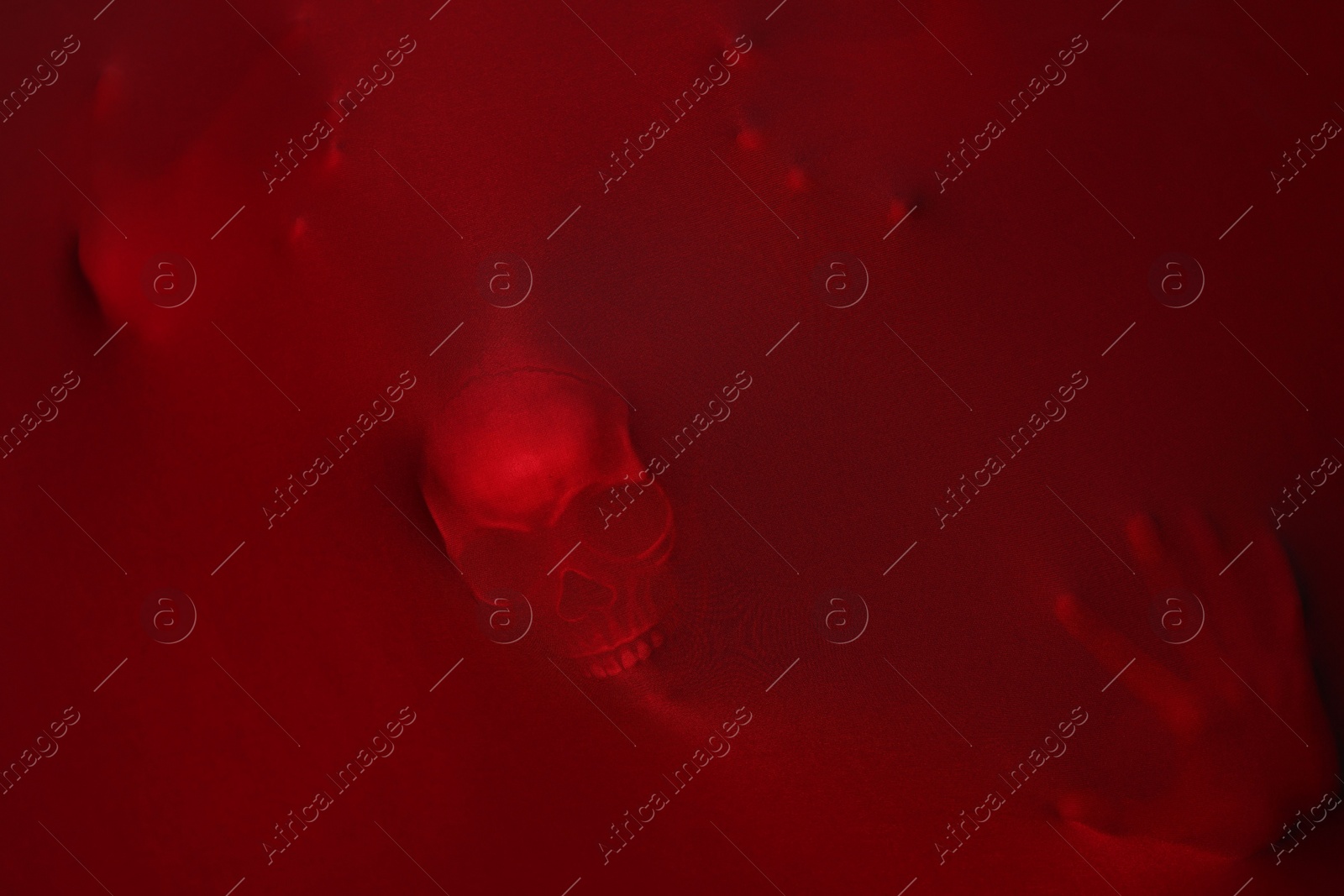 Photo of Silhouette of creepy ghost with skull behind red cloth