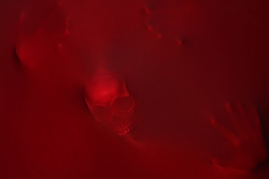 Silhouette of creepy ghost with skull behind red cloth