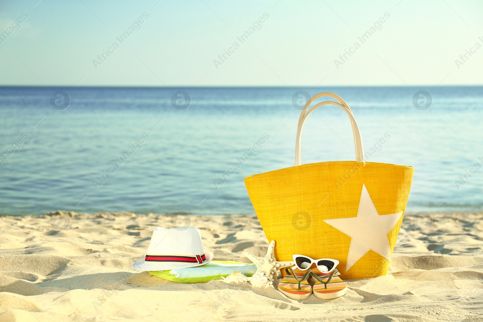 Photo of Composition with stylish beach accessories on sand near sea. Space for text