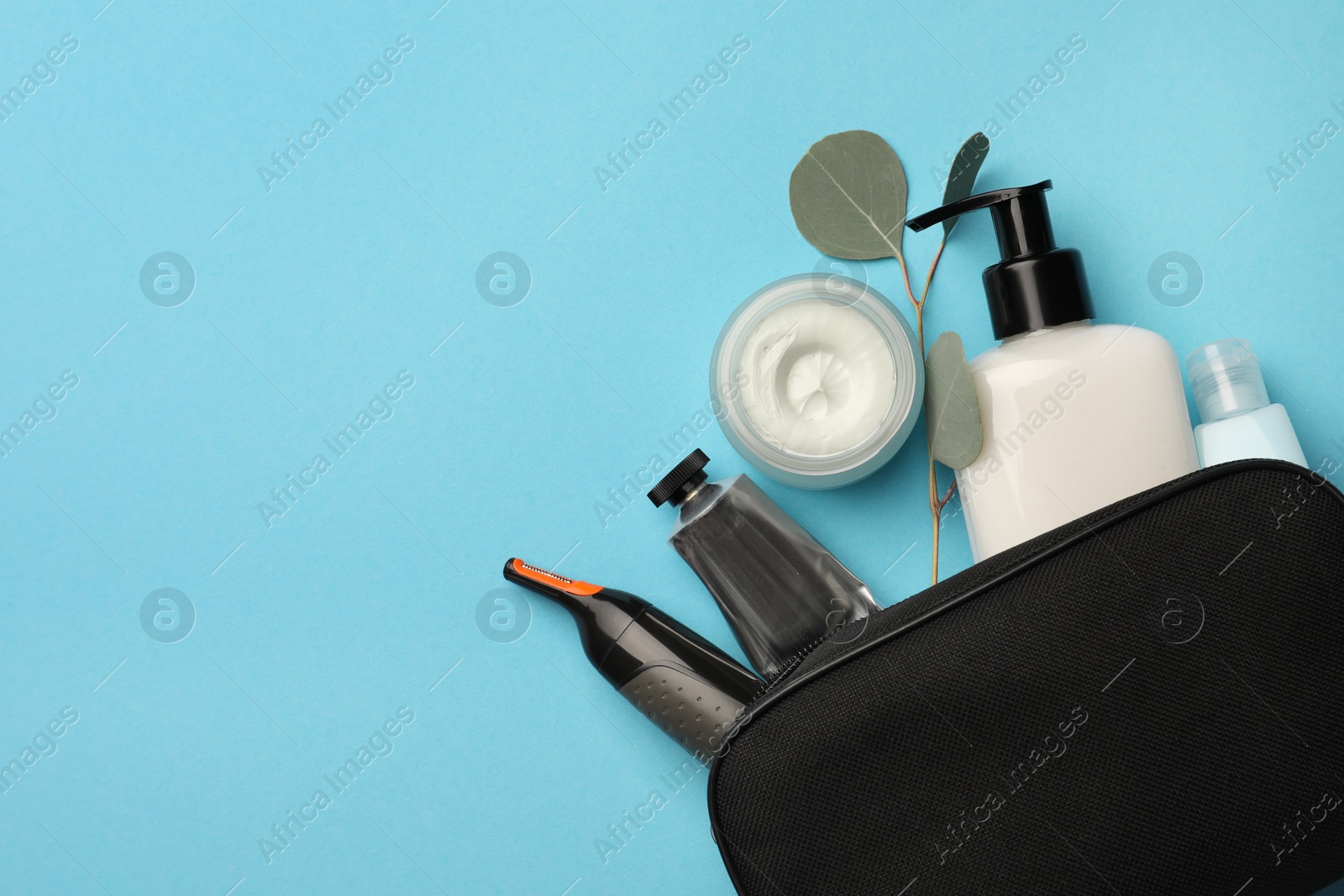 Photo of Preparation for spa. Compact toiletry bag with different cosmetic products and eucalyptus on light blue background, flat lay. Space for text