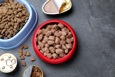 Photo of Wet and dry pet food on grey table, flat lay. Space for text