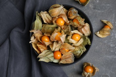 Ripe physalis fruits with dry husk on grey table, flat lay