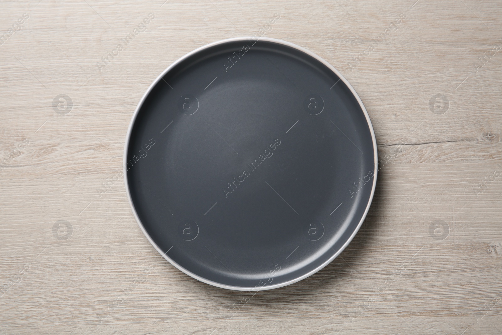 Photo of One ceramic plate on light wooden table, top view