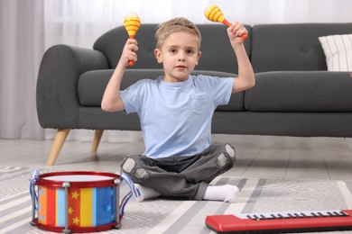 Photo of Little boy playing toy maracas at home
