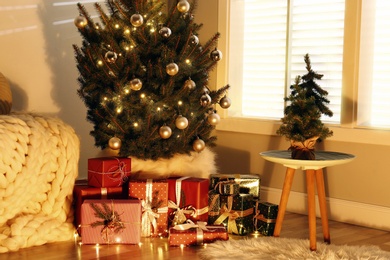 Photo of Beautiful Christmas tree and gift boxes near window in room. Interior design