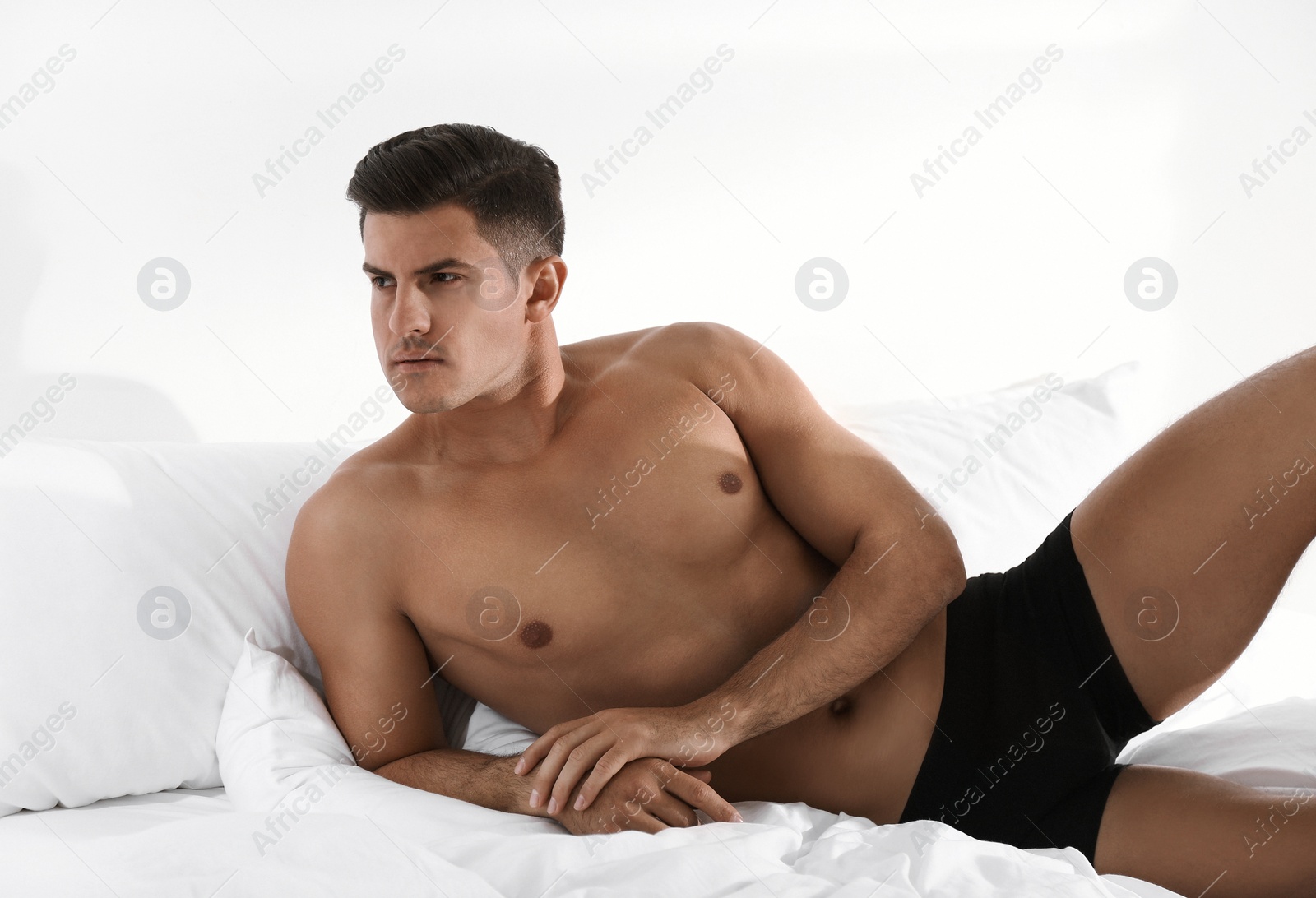 Photo of Handsome man in black underwear on bed indoors