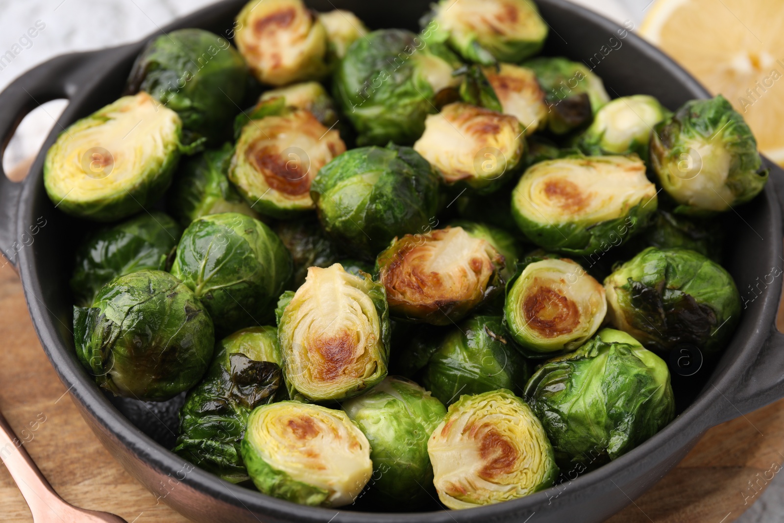 Photo of Delicious roasted Brussels sprouts in baking dish on table, closeup