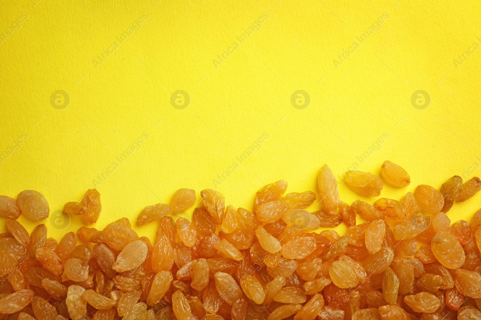 Photo of Many raisins on color background, top view with space for text. Dried fruit as healthy snack