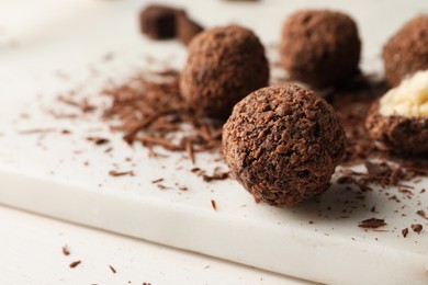 Many delicious chocolate truffles on white board, closeup. Space for text