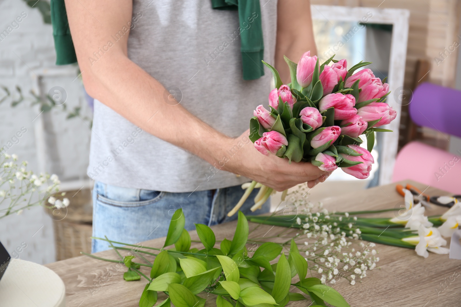 Photo of Male decorator creating beautiful bouquet at table