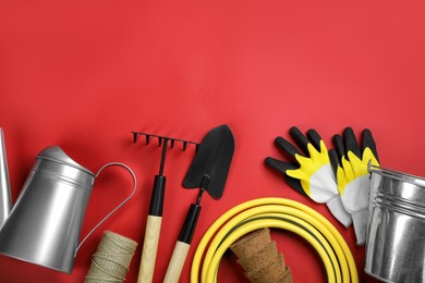 Flat lay composition with gardening tools on red background, space for text