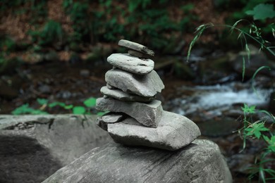 Photo of Many stacked stones near stream in forest