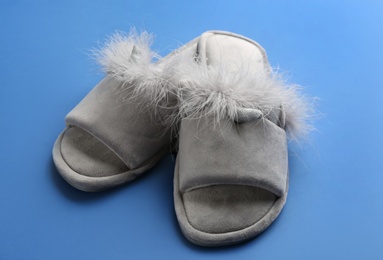 Pair of stylish soft slippers on blue background