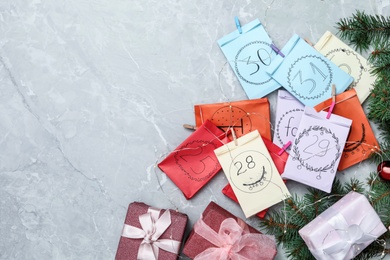 Photo of Flat lay composition with colorful paper bags and fir branches on grey marble table, flat lay with space for text. New Year advent calendar