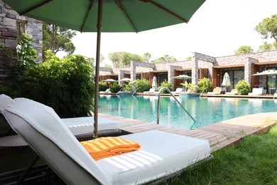 Photo of Sunbeds near outdoor swimming pool at luxury resort