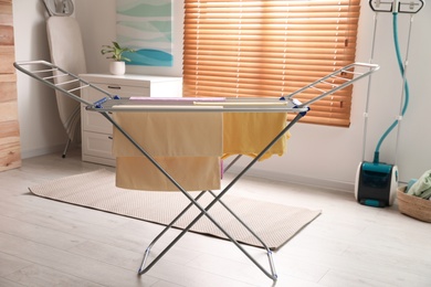 Photo of Clean laundry hanging on drying rack indoors