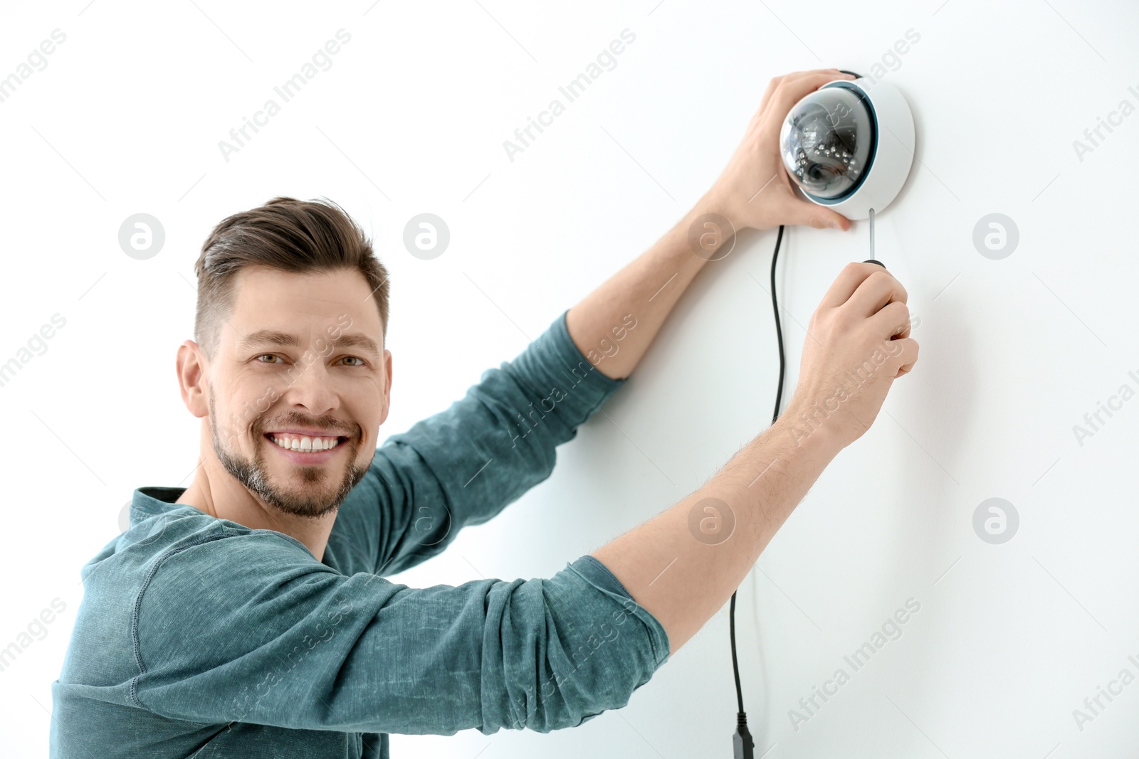 Photo of Technician installing CCTV camera on wall indoors