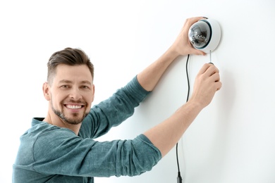 Photo of Technician installing CCTV camera on wall indoors