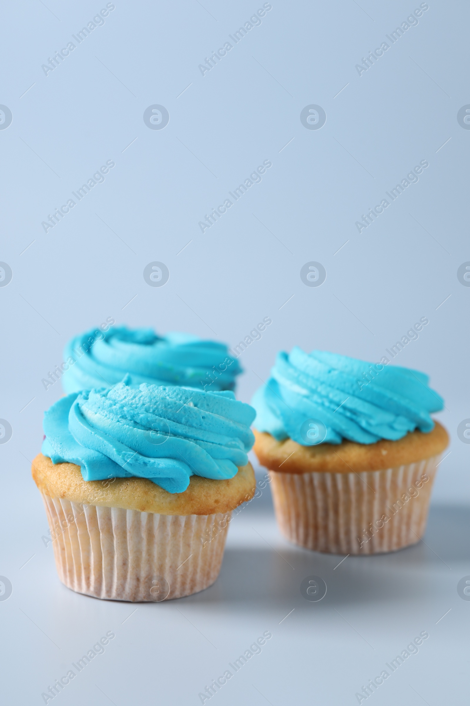 Photo of Delicious cupcakes with bright cream on light background, space for text