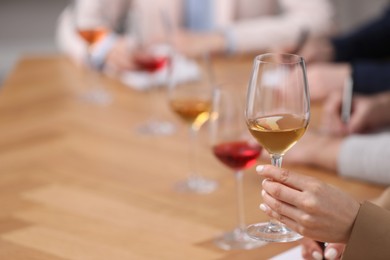 Photo of Sommeliers tasting different sorts of wine at table indoors, closeup