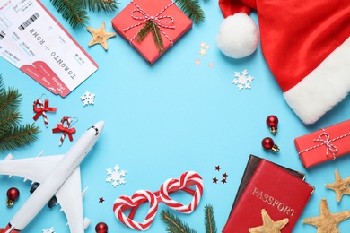 Photo of Frame of Christmas decorations, airline tickets and space for text on light blue background, flat lay. Winter vacation