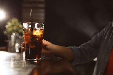 Photo of Woman with glass of refreshing cola at bar counter, closeup