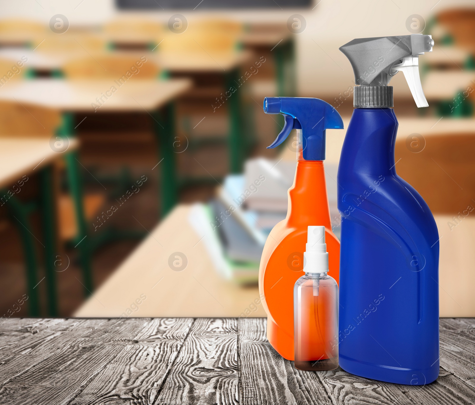 Image of Protective measures during Coronavirus pandemic. Bottles of disinfectant and hand sanitizer on table against classroom, space for text