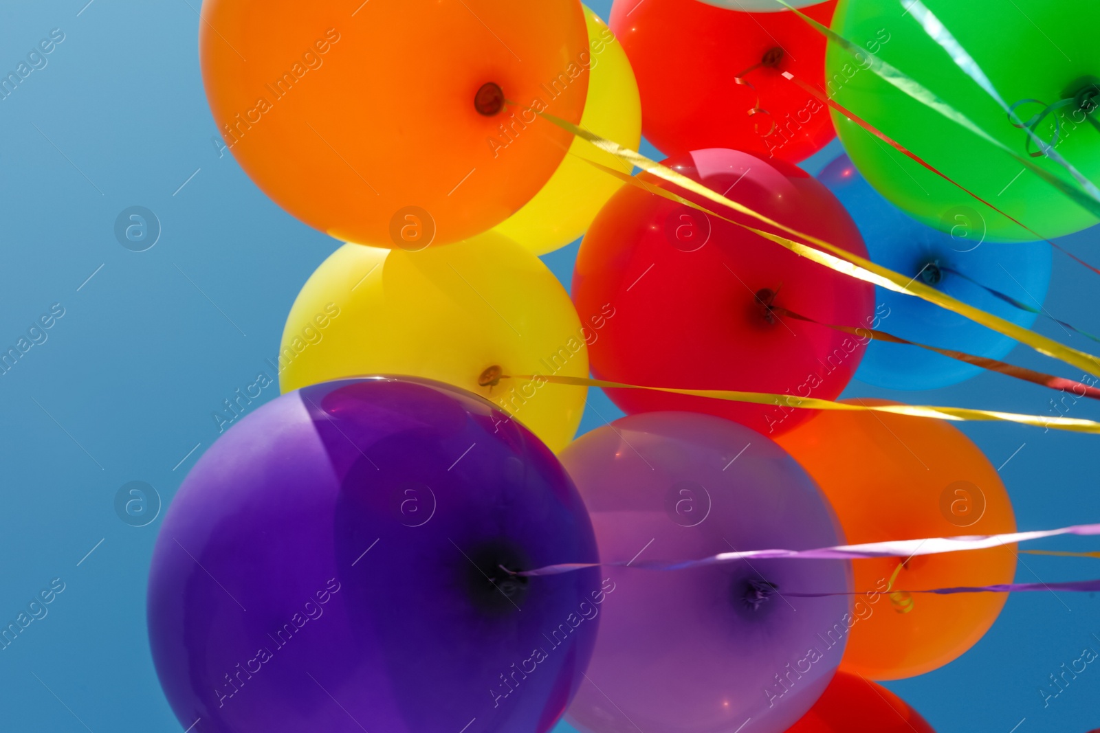 Photo of Bunch of colorful balloons against blue sky, bottom view