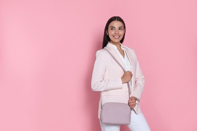 Photo of Beautiful young woman with stylish bag on pink background, space for text