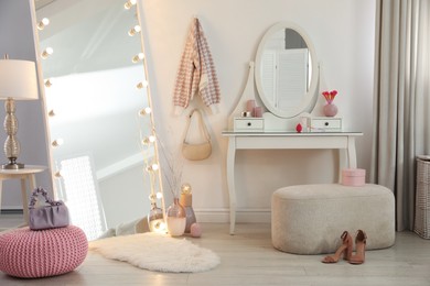 Photo of Large mirror with light bulbs and dressing table in stylish room. Interior design