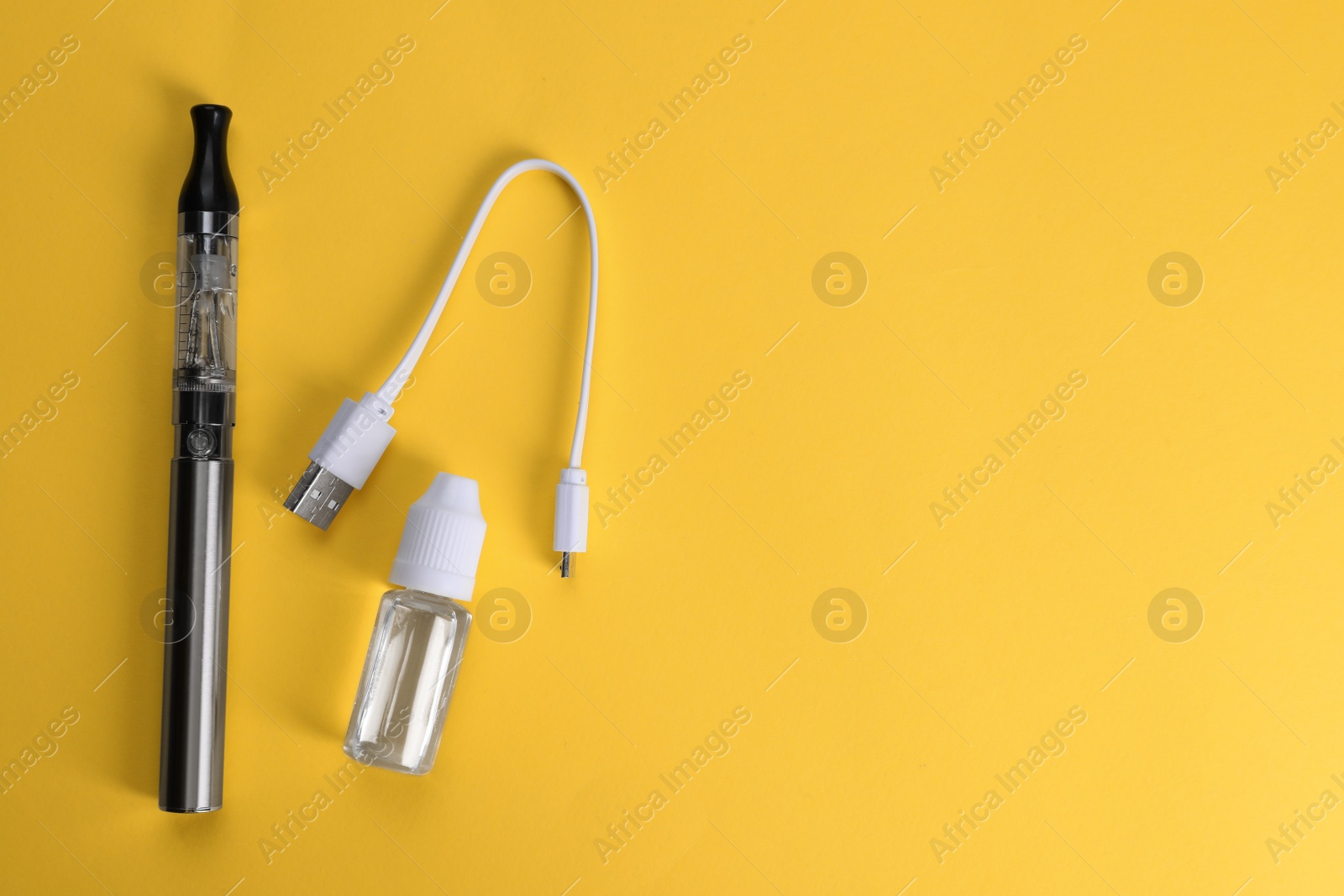 Photo of Reusable electronic cigarette, vaping liquid and USB charger on yellow background, flat lay. Space for text