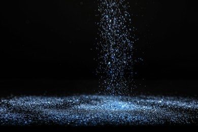 Photo of Shiny blue glitter falling down on black background. Bokeh effect